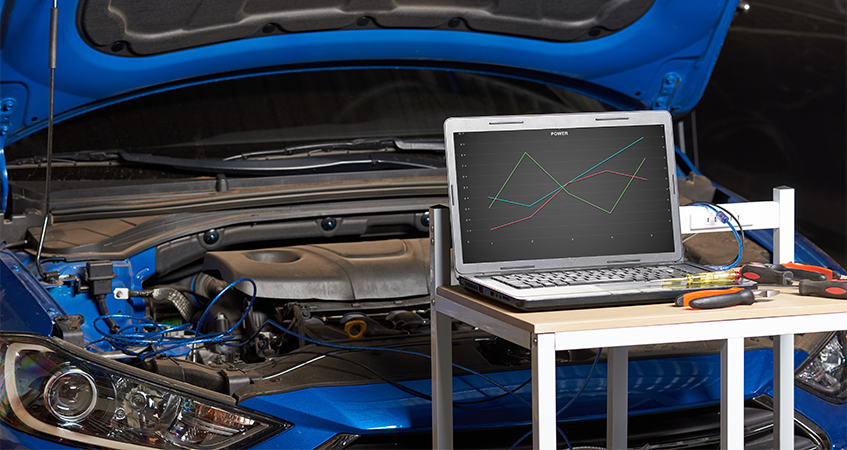 Laptop on trolley in front of car with bonnet open, running diagnostics